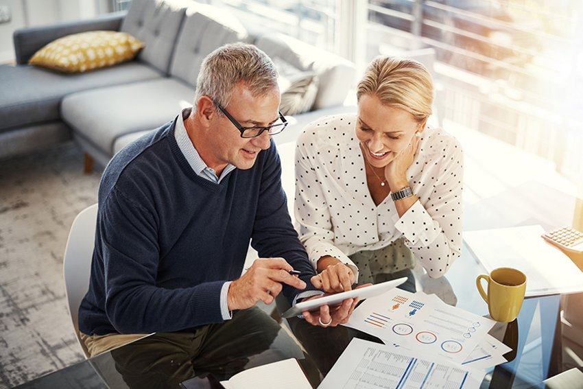869595964 Shot of a mature couple using a digital tablet while going through paperwork at home